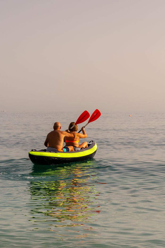 about-us-02 A couple kayaking on a tranquil ocean during a clear summer day.